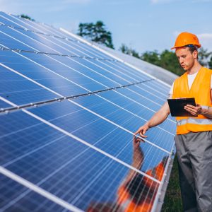 Man worker in the firld by the solar panels